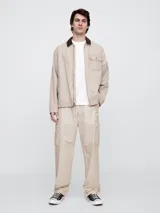 Pantalón cargo de corte holgado, confeccionado en popelina color beige, con cintura elástica ajustable mediante cordón y bolsillos laterales tipo cargo.