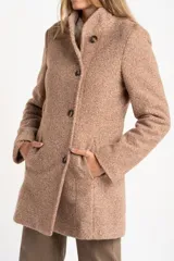 Tapado de poliéster con textura en color beige, de calce al cuerpo. Cuenta con cuello alto, cierre frontal de botones oscuros y bolsillos laterales.