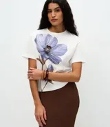 Remera de corte boxy confeccionada en algodón, con cuello redondo y mangas cortas. Presenta un estampado frontal de una flor grande en tonos violetas con detalles bordados.