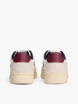 Zapatillas de corte bajo Tommy Jeans, confeccionadas en una combinación de cuero y ante en tonos blanco, beige y burdeos. Presentan suela cupsole de goma en color crema, cordones moteados y el logo de la marca en el lateral.