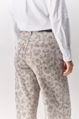 Pantalón de jean tiro medio con corte wide leg y estampado animal print. Presenta costuras verticales frontales y diseño de pierna amplia.