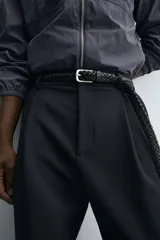 Pantalón de corte relajado en color verde militar, con diseño de pliegues frontales, bolsillos laterales y cierre de cremallera con botón.