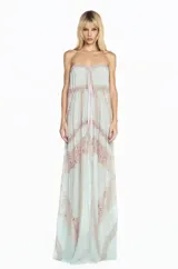 Vestido largo de corte fluido confeccionado en chiffon color verde agua, con diseño strapless y detalle de lazo frontal. Presenta paneles verticales de encaje en tono beige que recorren la prenda, aportando textura y un estilo romántico.