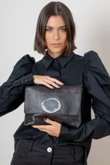Sobre de cuero color suela con solapa frontal decorada con una piedra de ágata natural enmarcada en metal. Incluye correa larga ajustable y extraíble para usar como bandolera.