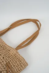 Bolso tipo tote de tejido estilo rafia en color beige, con asas dobles de hombro y cordones ajustables de cuero sintético marrón.