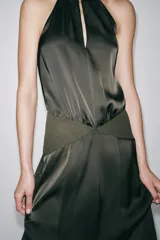 Vestido largo de cuello halter con tirantes finos y hombros descubiertos. Presenta un diseño con costuras marcadas, forro interior a tono y cierre lateral con cremallera oculta.