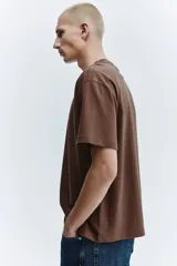 Remera de algodón color marrón, con cuello redondo y diseño de corte relajado con hombros caídos.