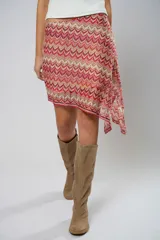 Minifalda asimétrica de crochet con diseño de ondas en tonos rojo, rosa y beige.