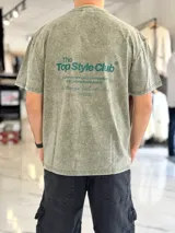 Remera oversize de efecto acid wash en color verde militar, con mangas cortas y estampa tipográfica en la espalda con el texto 'The Top Style Club'.