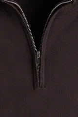 Buzo de punto fino color marrón oscuro, con cuello alto acanalado y medio cierre frontal. Presenta remates acanalados en puños y bajo.