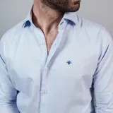 Camisa negra de algodón con cuello clásico, manga larga y cierre frontal con botones. Presenta un logo bordado en el pecho. Corte entallado.