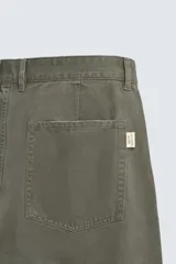 Pantalón de corte carrot fit confeccionado en tejido de algodón con estructura diagonal y efecto lavado. Presenta bolsillos frontales con bolsillo cerillero, bolsillos traseros de plastrón y cierre frontal con cremallera y botón.
