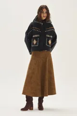 Campera de lana merino hervida en color crudo, con diseño de cuello camisero, cierre frontal de botones y bolsillos frontales. Presenta bordados artesanales con motivos geométricos en tonos marrón y azul en el frente, espalda y mangas.