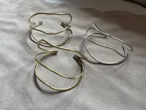 Pulsera rígida de metal con tres aros irregulares, disponible en alpaca color plateado o bronce color dorado.