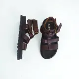 Sandalias de cuero marrón con tiras anchas y hebilla lateral.