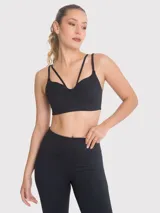 Top deportivo negro con diseño de tiras cruzadas en el frente, escote pronunciado y banda elástica inferior. Cuenta con almohadillas removibles y ofrece soporte medio.