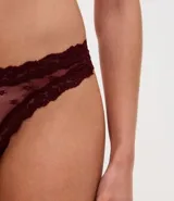 Kit de tres bombachas tipo bikini confeccionadas en encaje floral con forro de algodón. El set incluye una prenda roja, una bordó y una negra.