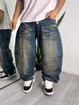 Pantalón jean baggy de corte ancho, color azul oscuro con efecto desgastado u óxido y estampado láser con motivos gráficos y texto en tono dorado.