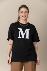 Remera gris con estampa de la letra M en negro y cadena plateada en el cuello.