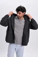 Campera gris oscuro con textura, capucha con cordón ajustable, cierre frontal y bolsillos frontales con solapa.