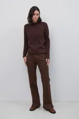 Polera de tejido de punto fino en color beige, con cuello alto y mangas largas con puños acanalados.
