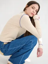 Polera de manga larga confeccionada en tela rib color bordó, con cuello alto y hombreras. Presenta costuras a la vista con pespuntes en hilo de color contrastante en el cuello, puños, hombros y ruedo.