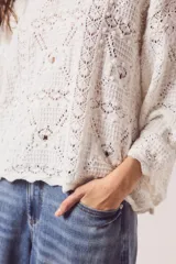 Sweater de tejido de punto calado color marrón, con diseño oversize, cuello redondo y mangas tres cuartos.