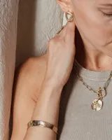 Pulsera tipo esclava abierta con diseño rústico y acabado irregular, fabricada en bronce y alpaca.