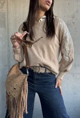 Sweater de punto color beige, con cuello redondo y mangas largas abullonadas. Presenta detalles bordados con lentejuelas y perlas en los hombros y parte superior de las mangas.