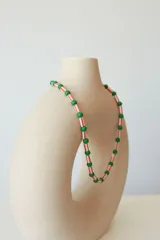 Collar tipo choker de cuentas plásticas en colores verde lima y amarillo, con diseño de cuentas cilíndricas y esféricas intercaladas. Incluye una cadena de extensión para ajustar el largo.