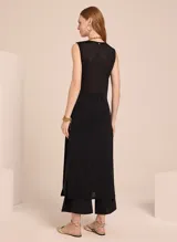 Túnica negra sin mangas de tricot con escote redondo, detalle de broche dorado superpuesto y aberturas laterales.