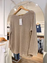 Sweater liviano de tejido calado en color beige, con escote redondo, mangas largas y calce amplio y relajado.