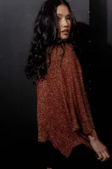 Buzo de tejido ligero con efecto metalizado en tonos rojizos y dorados, escote amplio y mangas anchas.