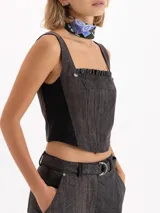 Top de gabardina con efecto batik, corte ajustado al cuerpo y largo hasta la cintura. Presenta escote cuadrado con detalle de volados en cuero vacuno, breteles anchos y apliques de remaches metálicos en forma de flor en el frente.
