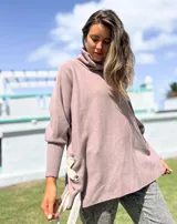 Polerón de cuello alto y corte oversize, color rosado, con mangas largas de puño acanalado y detalle de ojalillos metálicos con tiras en los laterales.