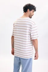 Remera oversize de manga corta con diseño de rayas horizontales en tonos beige, marrón y blanco, con cuello redondo.