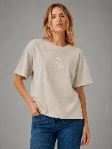 Remera de algodón color beige con efecto acid wash, corte oversize y mangas cortas. Presenta un delicado bordado frontal con la letra M y el texto "MOOD JUST HAPPY".