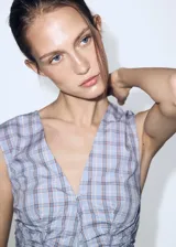 Blusa de popelín de algodón con estampado a cuadros, cuello en V y cierre frontal con botones. Diseño sin mangas y silueta entallada.