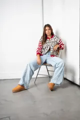 Saco de punto con diseño combinado, presenta un estampado animal print en el cuerpo y mangas con rayas horizontales en rojo y beige. Posee cuello redondo, cierre frontal con botones y terminaciones en tejido acanalado rojo.