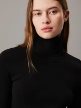 Vestido corto negro de punto de canalé, con cuello alto y mangas largas.