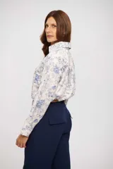 Camisa de manga larga color crema con estampado floral en tonos azules, cuello camisero y escote en V profundo.