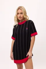 Vestido de tejido de punto negro con rayas verticales grises, corte recto y manga corta. Presenta ribetes de punto rojo en cuello, puños y ruedo, con costuras decorativas en hilo azul. Lleva un pequeño bordado de una letra 'B' estilizada en el pecho.