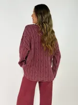 Sweater de punto con diseño de trenzas verticales, cuello redondo y mangas largas. Presenta un corte holgado y cómodo.