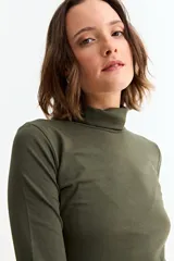 Remera básica de manga larga con cuello polera, confeccionada en tejido suave y elástico.