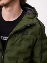 Campera puffer con capucha, color verde militar, con cierre frontal y bolsillos laterales. Presenta un diseño acolchado con costuras termoselladas y puños elásticos.