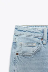 Jeans de tiro alto con diseño cropped flare, confeccionados en denim azul con acabado desgastado. Presentan cinco bolsillos, cierre frontal con cremallera y botón metálico, y bajo con terminación sin costuras.