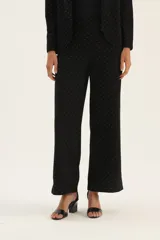 Pantalón negro con lunares blancos, de corte recto y tiro alto.