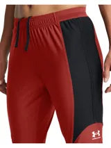 Pantalón deportivo Under Armour de corte ajustado, diseñado para fútbol. Presenta un diseño bicolor en rojo y negro con cintura elástica y cordón de ajuste interno. Incluye tecnología de secado rápido y tejido elástico en cuatro direcciones para mayor movilidad.