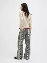 Pantalón tiro alto de pierna ancha con estampado animal print de serpiente en tonos beige, blanco y negro.