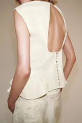 Camisa sin mangas de corte peplum y cuello redondo, confeccionada en hilatura con mezcla de lyocell con estampado jacquard floral tono sobre tono y cierre trasero con botón.